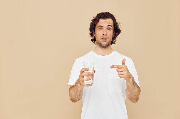 Cheerful man in a white Tshirt with a mug in hand beige background