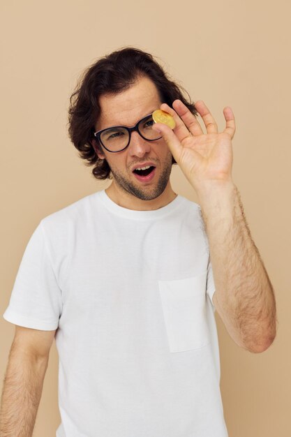 Cheerful man with glasses gold bitcoin in hands beige background