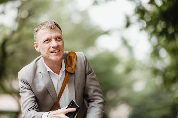 Cheerful mature businessman in formal clothing with bag waving and shouting out to someone in distance while travelling to office