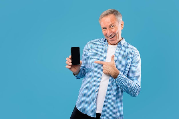 Cheerful mature man pointing finger at empty smartphone screen