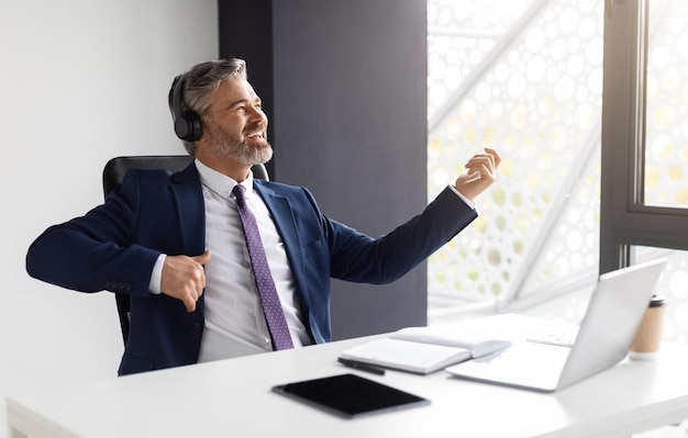 Cheerful middle aged businessman having fun at workplace in office