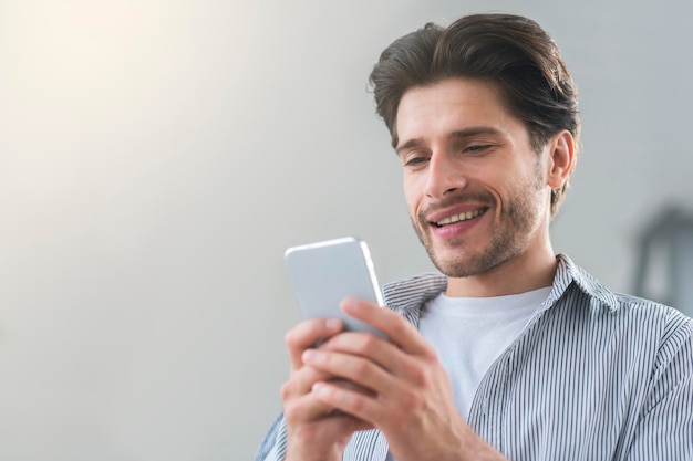 Cheerful millennial man texting with friend on cellphone