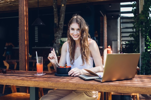 Cheerful modern adult female enjoying breakfast in resort cafe