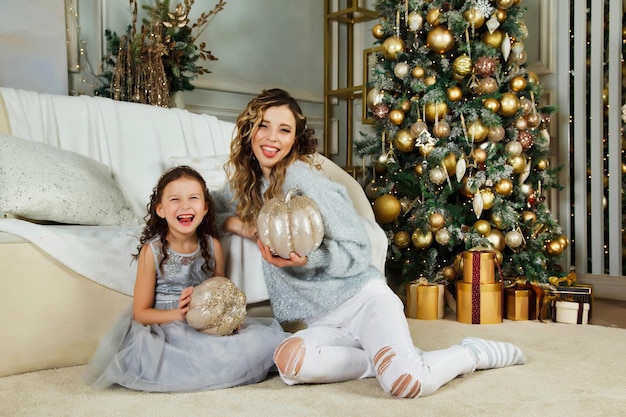 Cheerful mom and her cute daughter girl exchanging gifts on Merry Christmas and Happy New Year