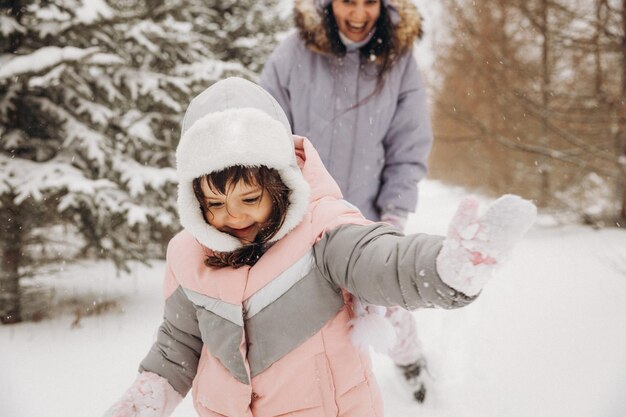 A cheerful mother catches up with her daughter, who runs through the snow in the forest. winter walks