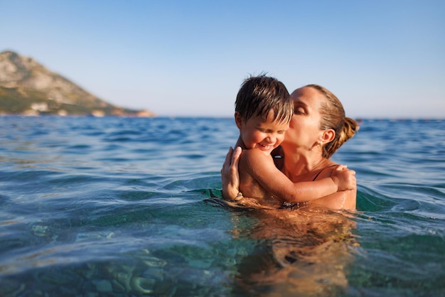 Cheerful mother plays with her son in the sea