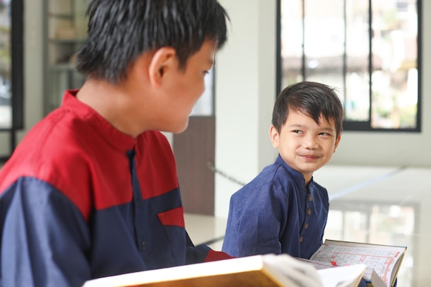 Cheerful Muslim Asian kid best friend smiling after reading quran together at the mosque