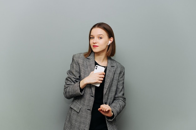 Cheerful office woman in smart casual clothes dancing with a smartphone in her hands to music