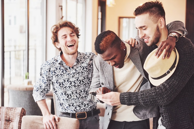 Cheerful old friends communicate with each other and phone watch in pub. Concept of entertainment and lifestyle. Wifi connected people in bar table meeting