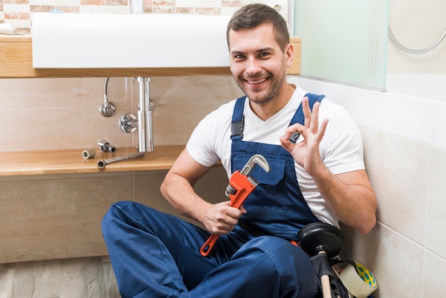 Cheerful plumber gesturing ok