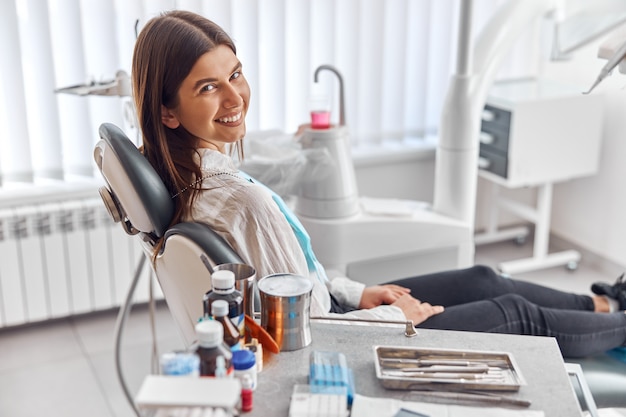 Cheerful positive client in dentistry. Female patient at dental procedure in modern dental clinic.