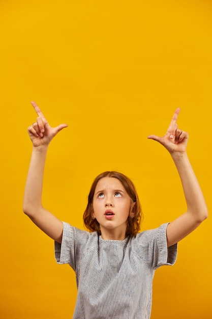 Cheerful positive ten years teen girl pointing fingers up