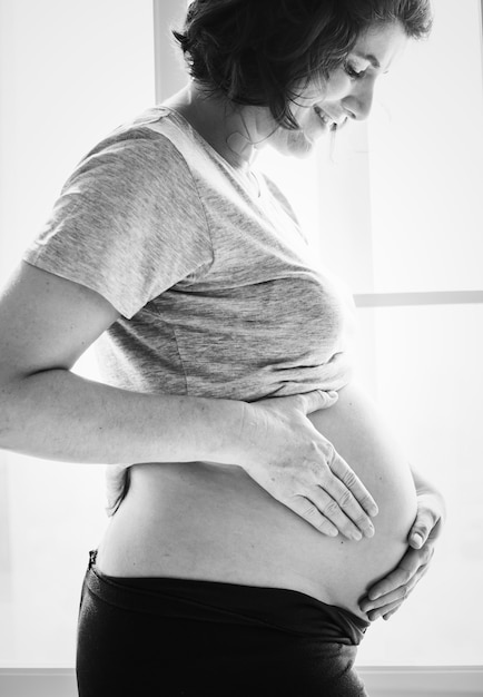 Cheerful pregnant woman standing by the window