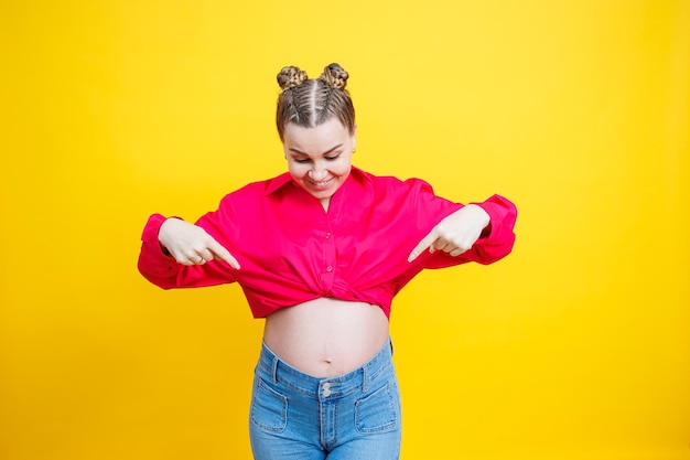 Cheerful pretty pregnant woman in a pink shirt on a yellow background Young bright pregnant woman