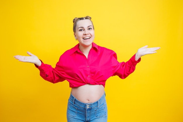 Cheerful pretty pregnant woman in a pink shirt on a yellow background Young bright pregnant woman