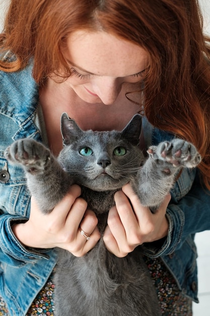 Cheerful redhead girl plays with her blue cat