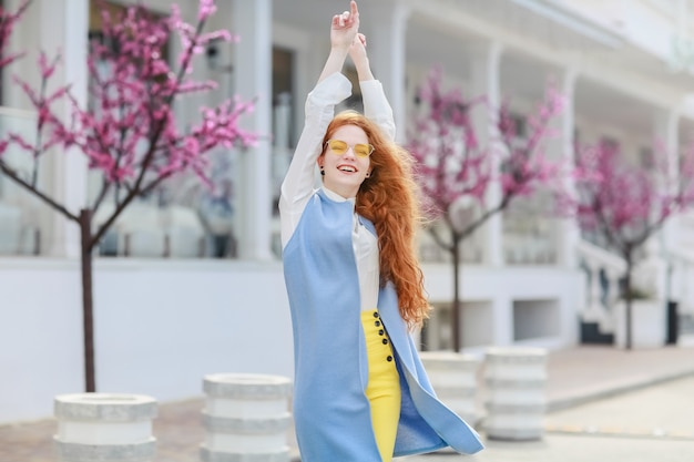 Cheerful redhead young woman in bright clothes on the street