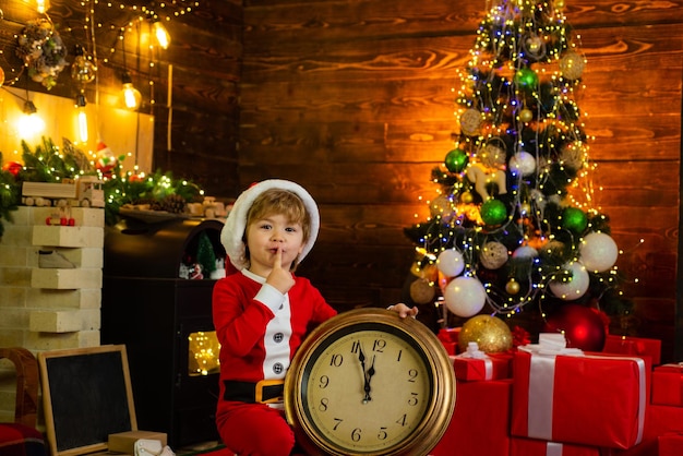 Cheerful Santa Elf kid holding clock Check contents of christmas stocking Christmas gifts Family hol