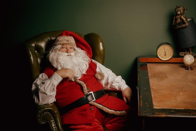 Cheerful santa sits in the house at the table christmas concept