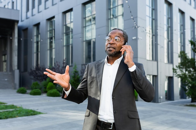 Cheerful and satisfied african american boss outside office building smiling and talking to