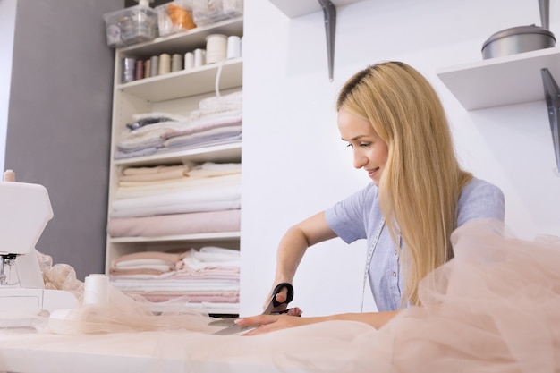 Cheerful seamstress sitting near sewing tools