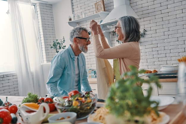 Cheerful senior couple preparing to cook a dinner and smiling while spending time at home