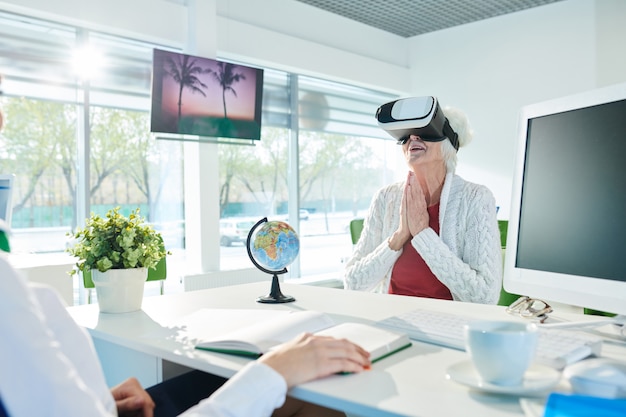 Cheerful senior lady watching 3D video of hotel presentation