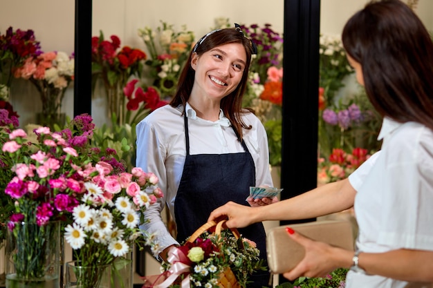 Cheerful small business entrepreneur woman orangery owner give flowers to client