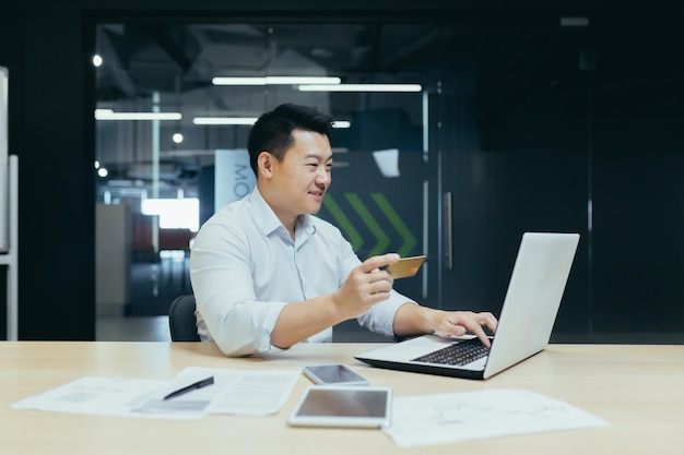 Cheerful and smiling asian businessman working in modern office