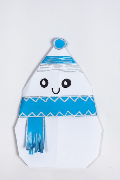 A cheerful snowman smiles origami in a hat and a scarf