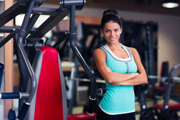 Cheerful sports woman standing with arms folded in fitness gym