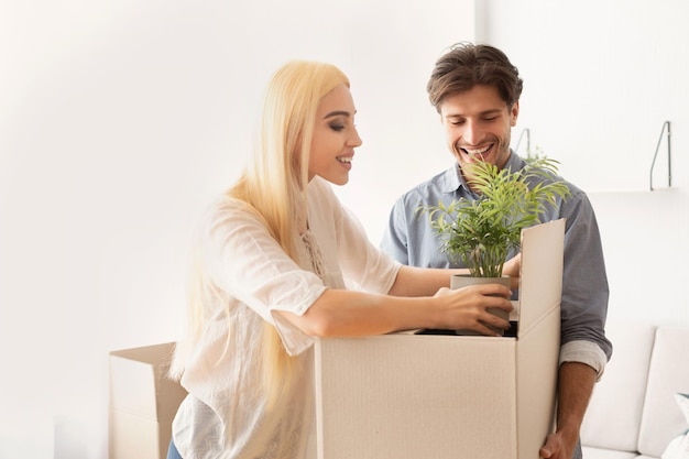 Cheerful Spouses Packing Things In Moving Boxes Preparing For Relocation