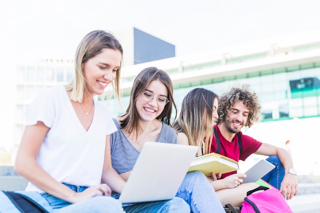 Cheerful students studying on street