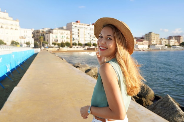 Cheerful stylish woman turns around and smiling at camera on Crotone promenade Calabria Italy