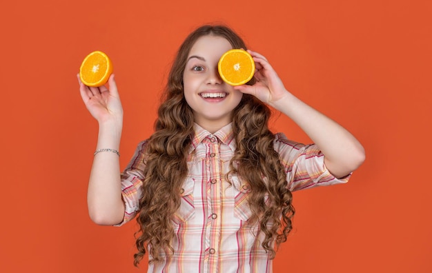 Cheerful teen girl hold citric fruit on orange background