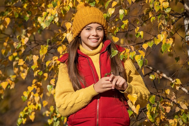 Cheerful teen kid at school time outdoor with autumn leaves