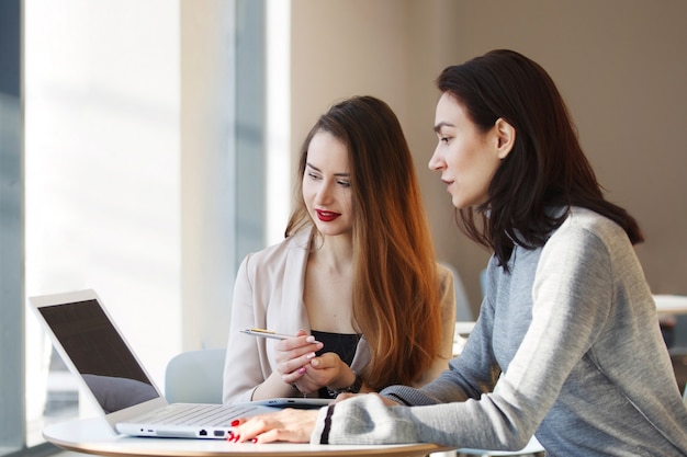 Cheerful two business women working at the office on a computer