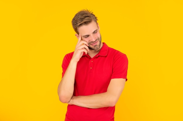 Cheerful unshaven young man in red shirt on yellow background skincare