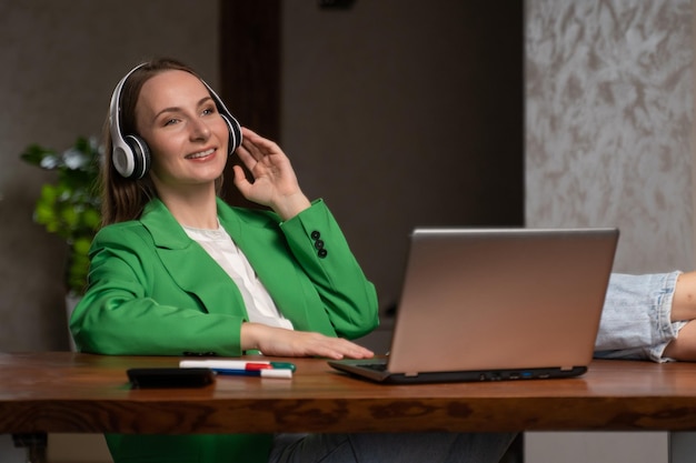 Cheerful woman enjoys music in headphones at workplace