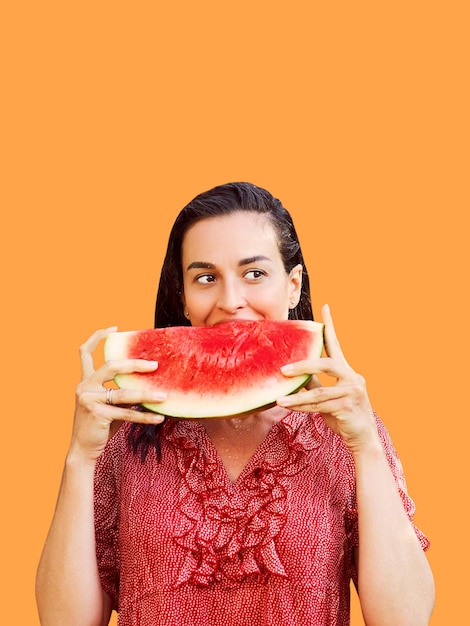 Cheerful woman holding a piece of sliced watermelon on a colorful background Summer concept