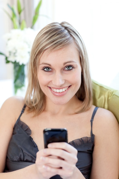 Cheerful woman sending a text sitting on a sofa 