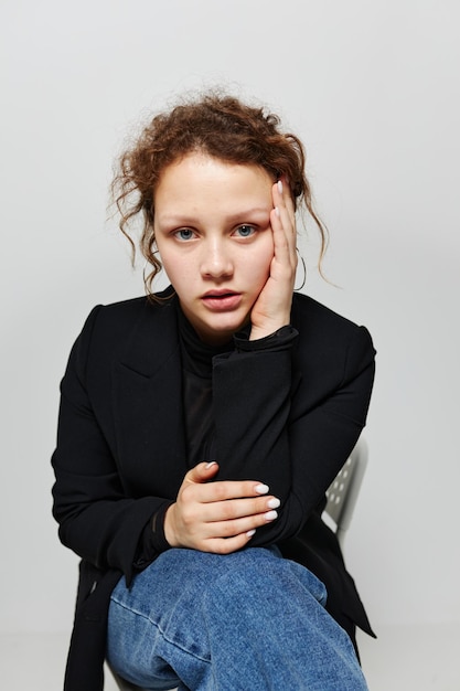 Cheerful woman sitting on a chair in a black jacket fashion posing light background unaltered