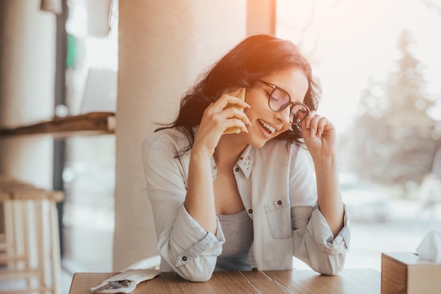 Cheerful woman speaking on phone in cafe