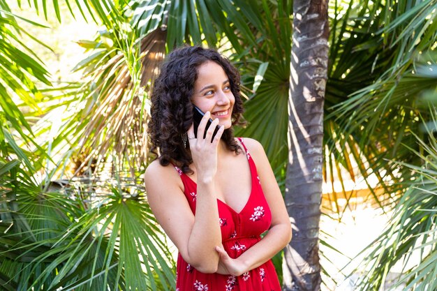 Cheerful woman speaking on smartphone in park