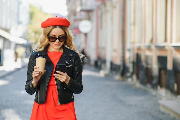 Cheerful woman in the street drinking morning coffee in sunshine light