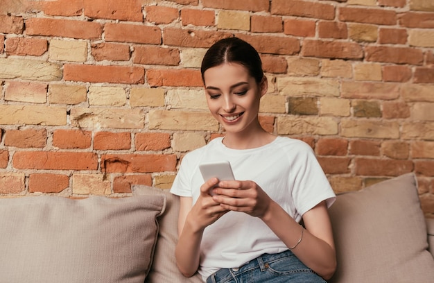 cheerful woman using smartphone in living room