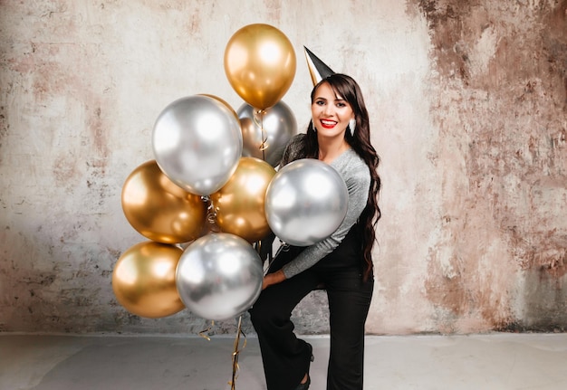 A cheerful woman with balloons laughs a young brunette with long hair celebrates her birthday helium balloons