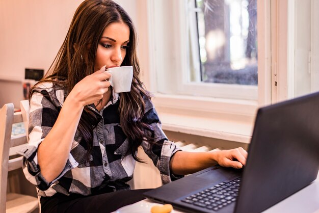 Cheerful woman working with laptop computer in cafe