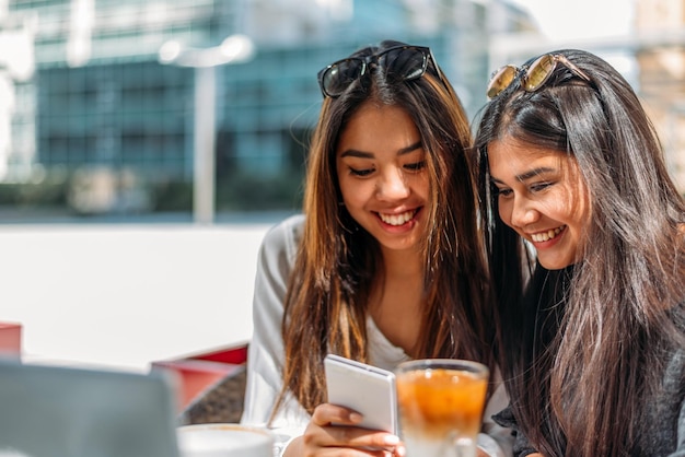 Cheerful women using tablet in street cafe