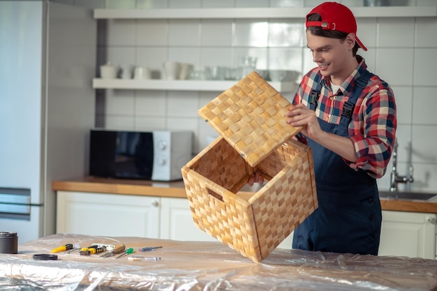 Cheerful woodworker assembling the box in the kitchen